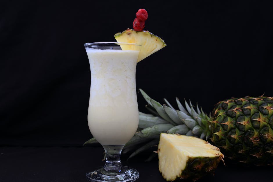 A smiling couple sitting on a beach, overlooking the ocean and holding piña coladas, representing financial serenity in retirement.