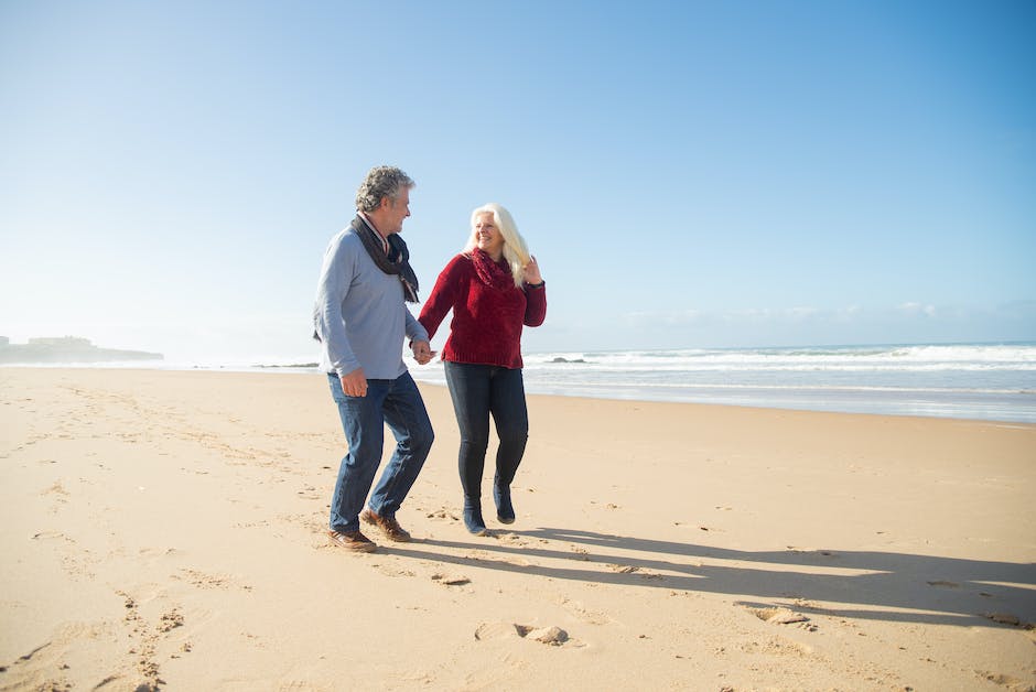 Image of a senior couple holding hands and smiling in front of a beach sunset, representing financial security and retirement planning