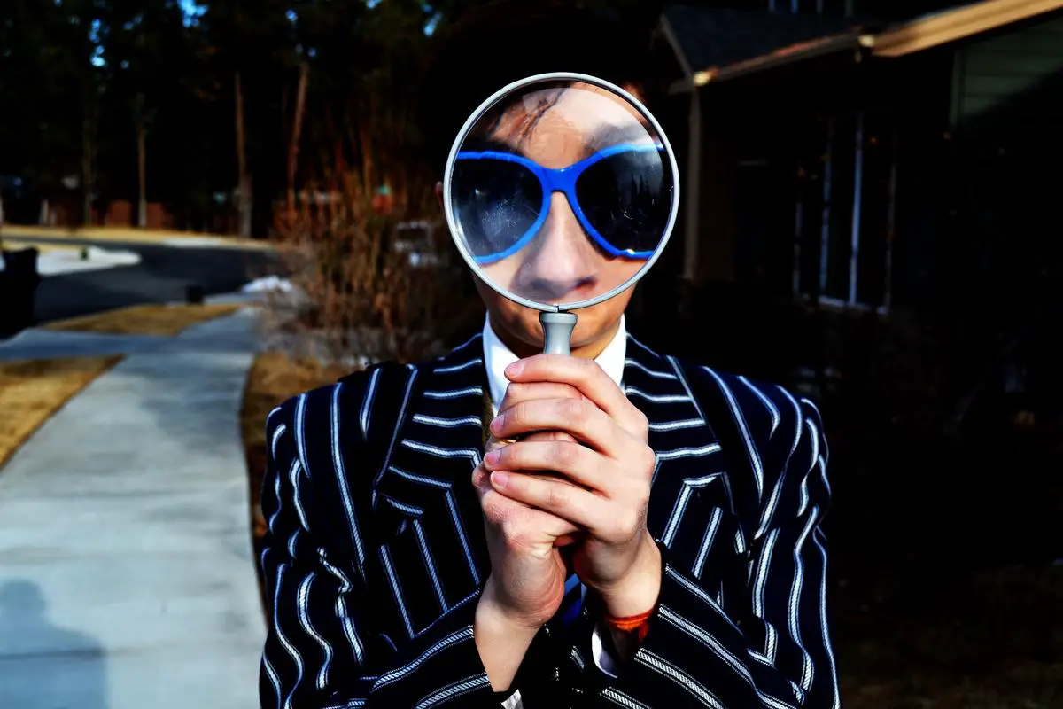 A person holding a magnifying glass, looking at a piece of paper with the words self-directed IRA on it.